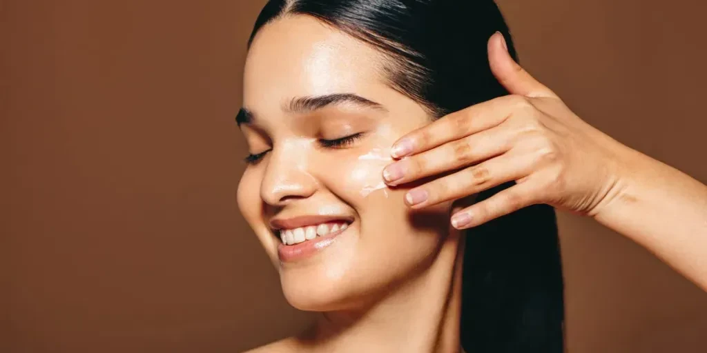 young woman with perfect skin applies facial cream