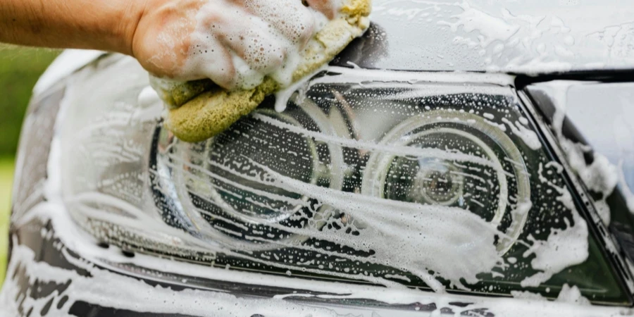 A Person Washing a the Headlight of a Car