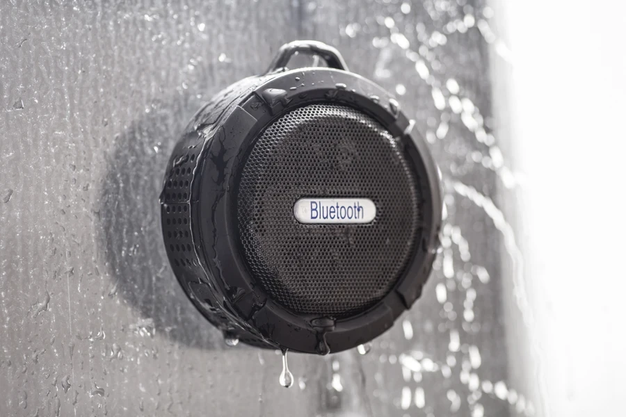 A black Bluetooth shower speaker on a wall