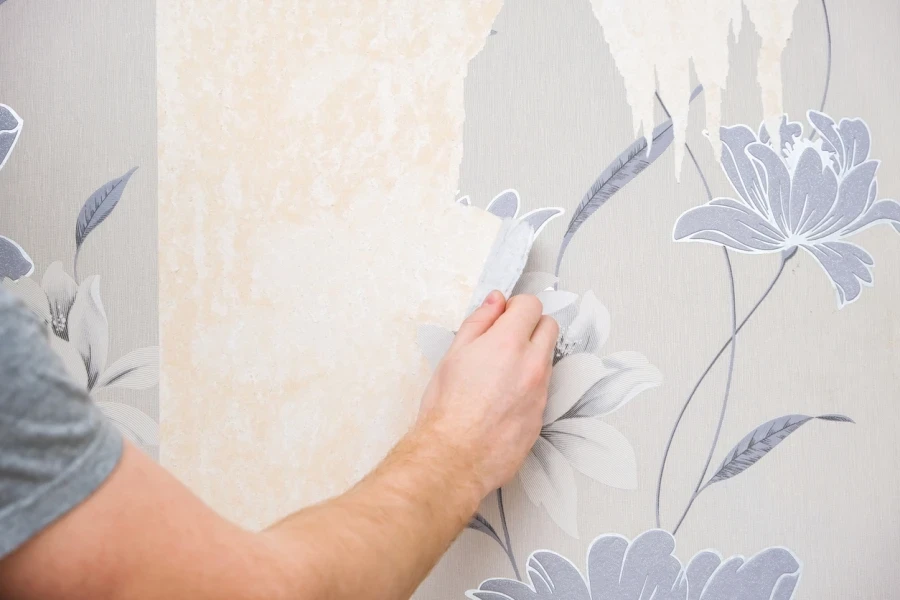 A person removing old wallpaper in a room