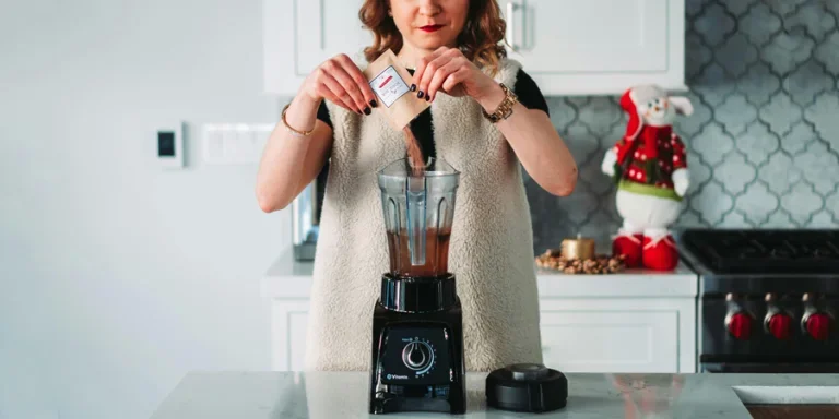 A woman pours a sachet into a blender in a festive kitchen setting
