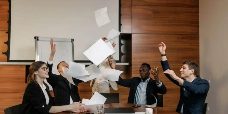 Businesspeople throwing sheets of paper in front of projector screen