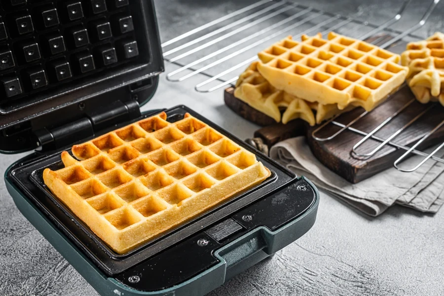 Cooking of fresh waffles in waffle maker. White background.