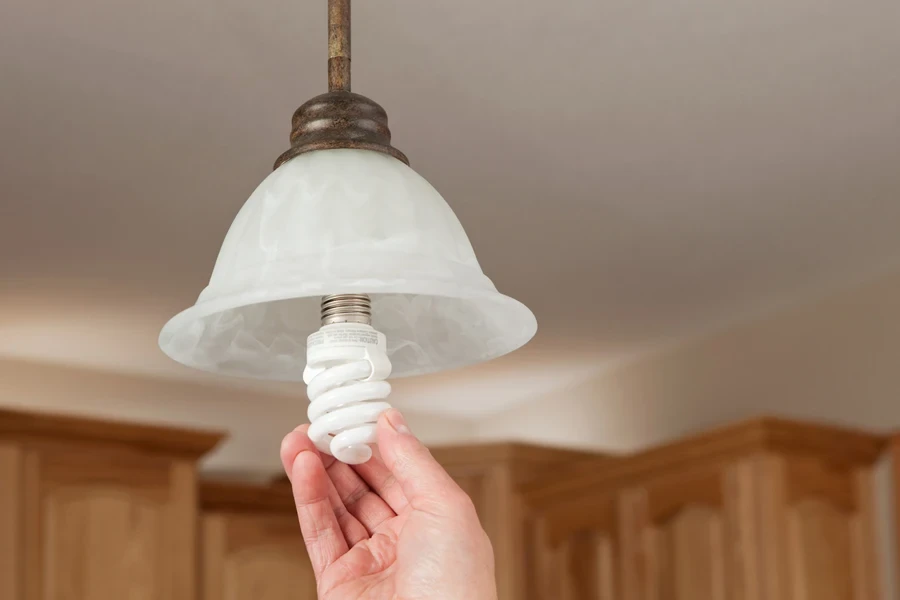 Hand installing compact fluorescent light bulb