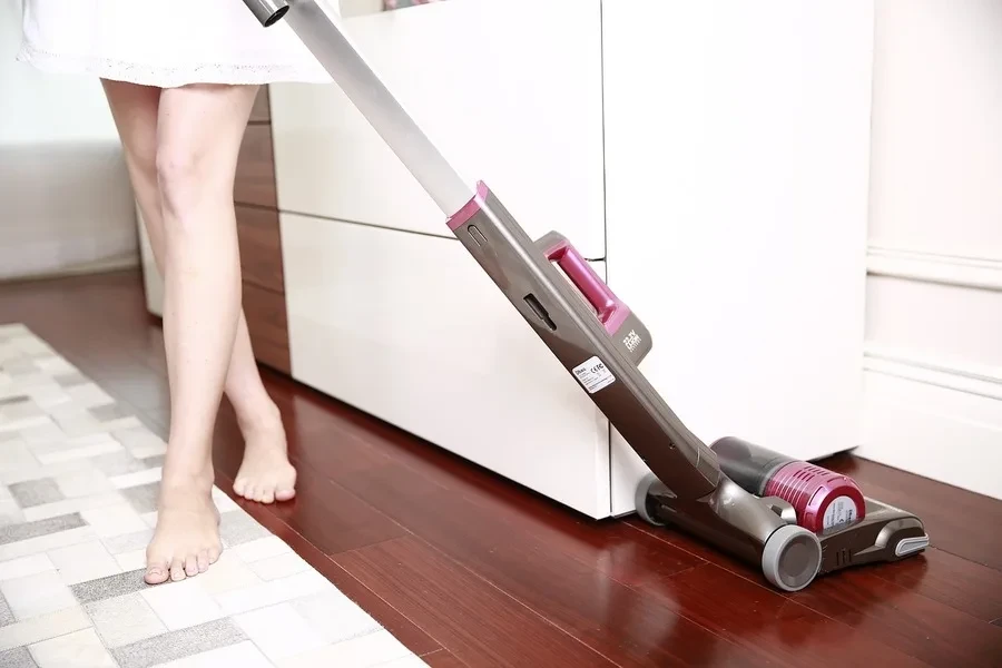 Person cleaning hardwood floor with a handheld vacuum cleaner