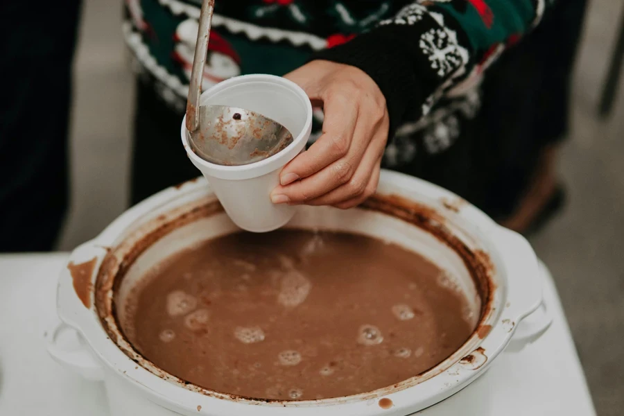 Person scooping hot chocolate out of a crockpot