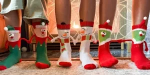 Three people wearing holding hands socks with Christmas designs