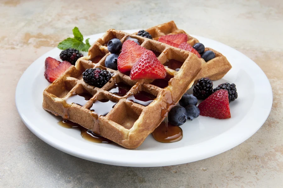 Two square waffles with fruit and syrup
