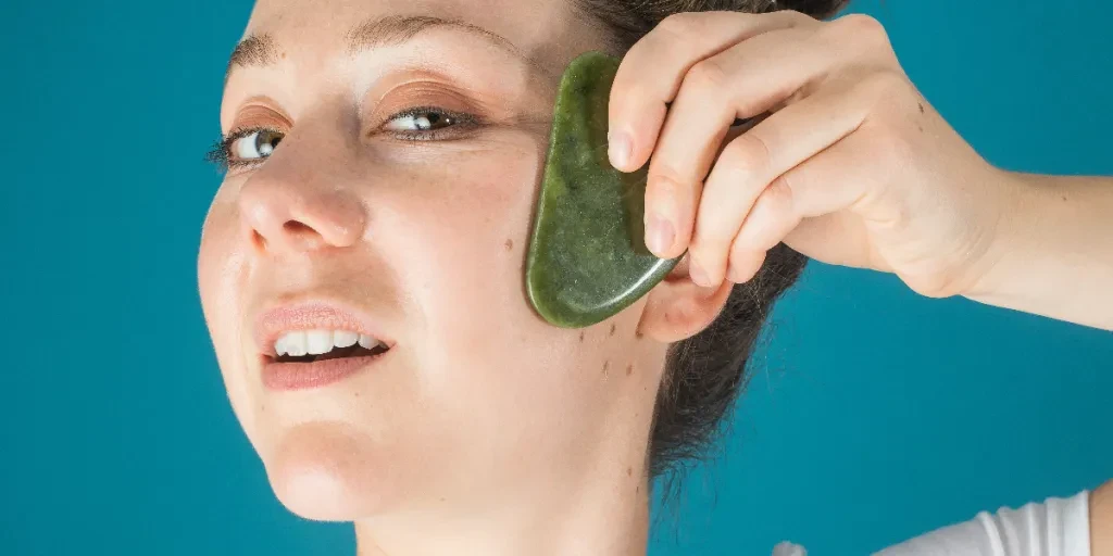 Woman Holds A Jade Face Massager To Her Face