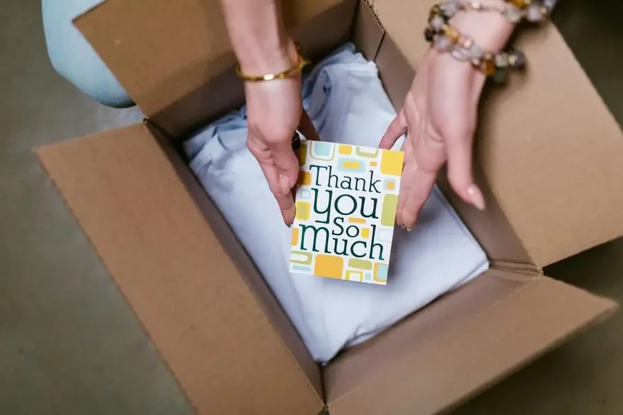 a person placing a thank-you card into a box