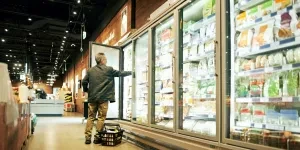 a person putting frozen food inside commercial freezer