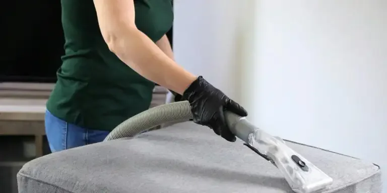 Person, die einen Ottomanen mit einem Handreiniger reinigt