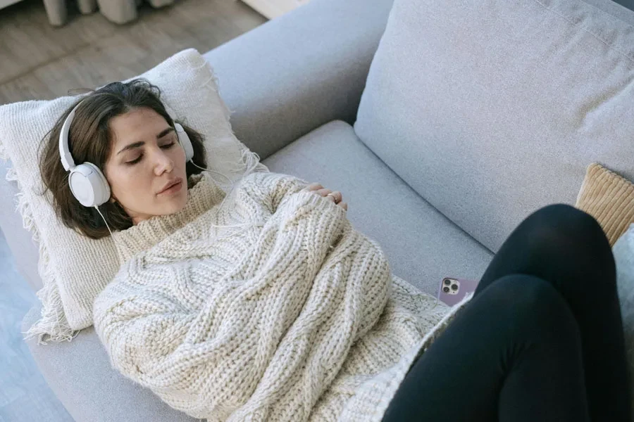 A Woman Wearing Headphone Lying on the Couch