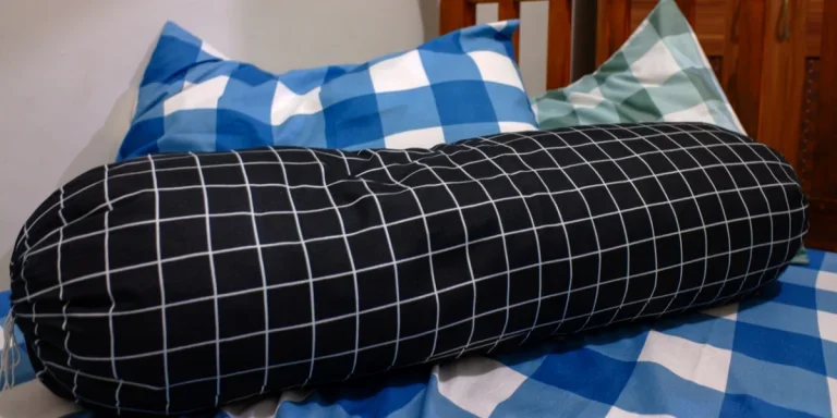 A bolster pillow on a mattress with pillows