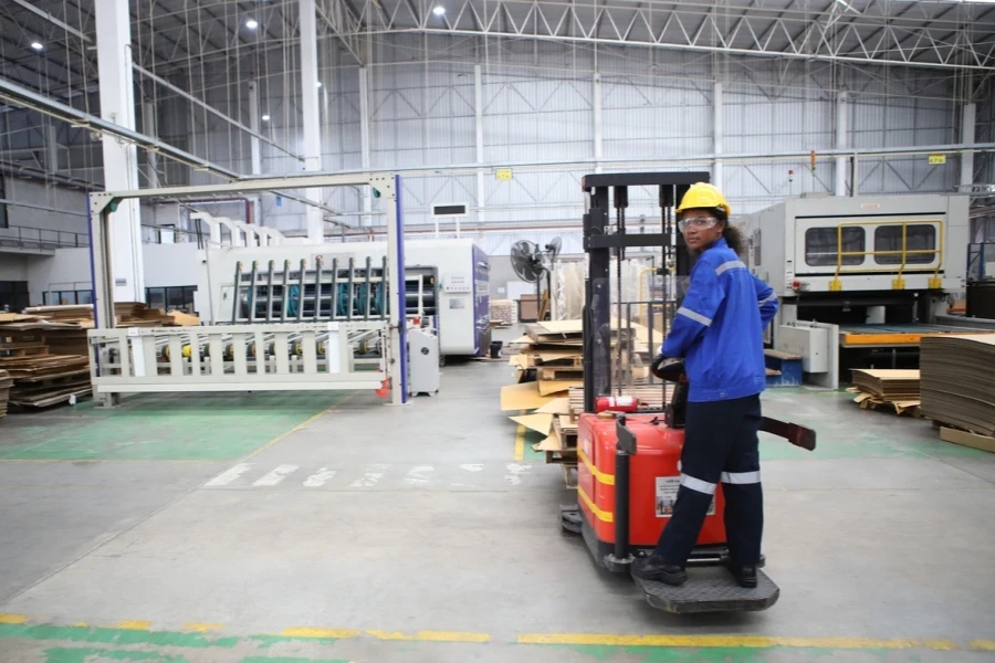 A factory worker riding on an electric stacker