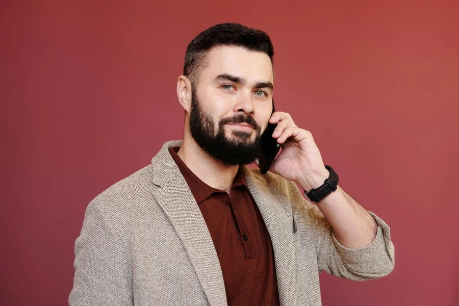 A man wearing a blazer and talking on phone