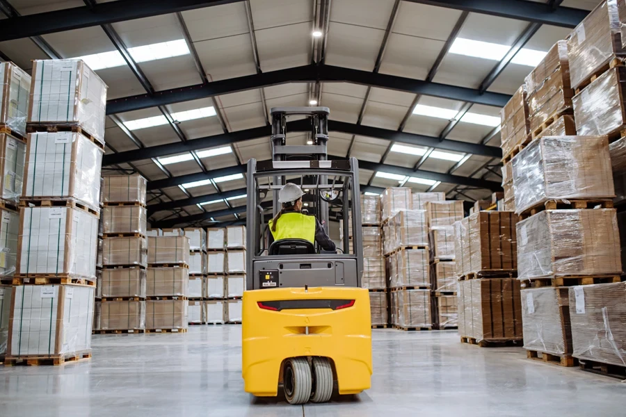 A worker driving a yellow lift truck