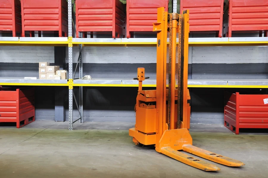 An orange electric stacker in a factory