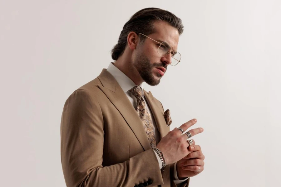 Homme barbu avec des lunettes regardant de côté et arrangeant des bagues