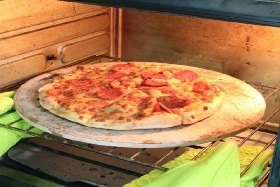 Ceramic pizza stone placed inside oven in home kitchen