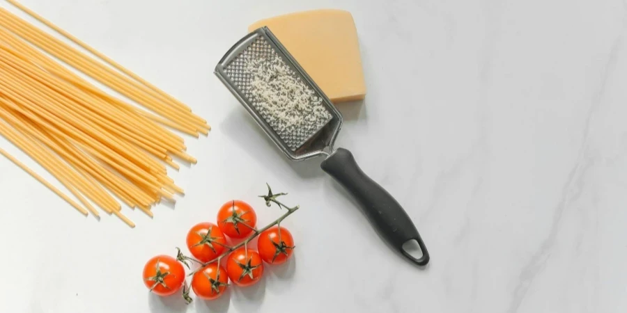 Cheese with Grater Beside Spaghetti and Tomatoes