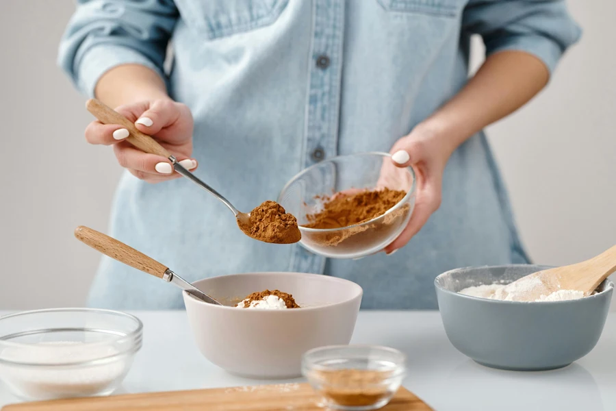 Close-up of hands measuring cocoa powder for home baking preparation