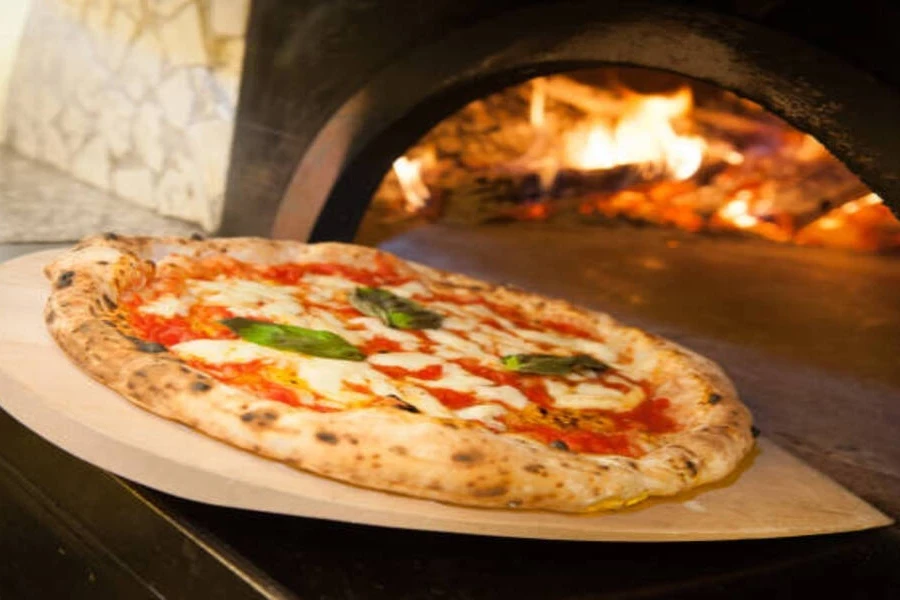Cordierite pizza stone being pulled out of high-heat oven