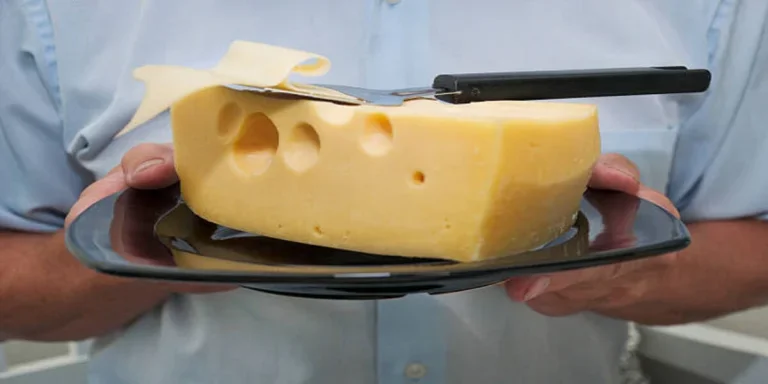 Large piece of Swiss cheese with cheese slicer on top