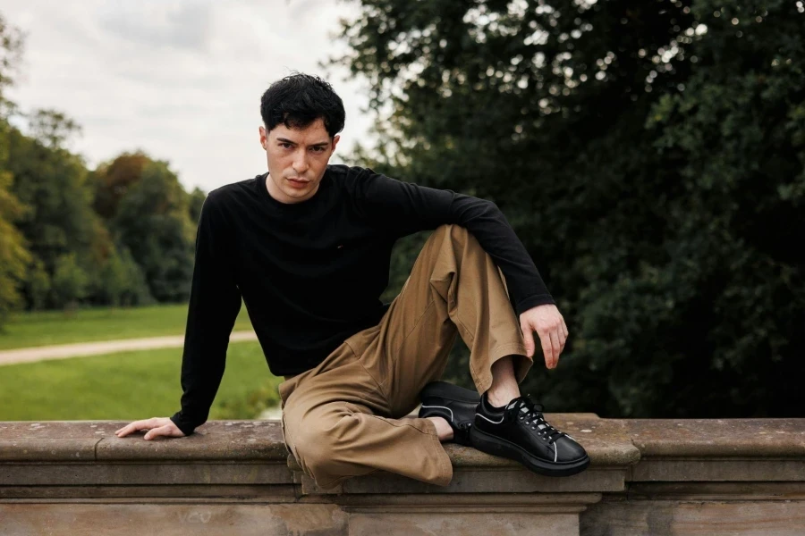 Man in Black Blouse Sitting on Wall