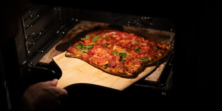 Person making pizza in an electric oven