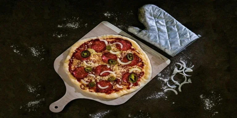 Raw pizza on wooden pizza stone with glove