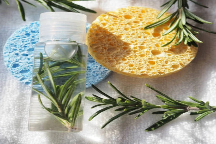 Rosemary water in plastic container next to bath sponges