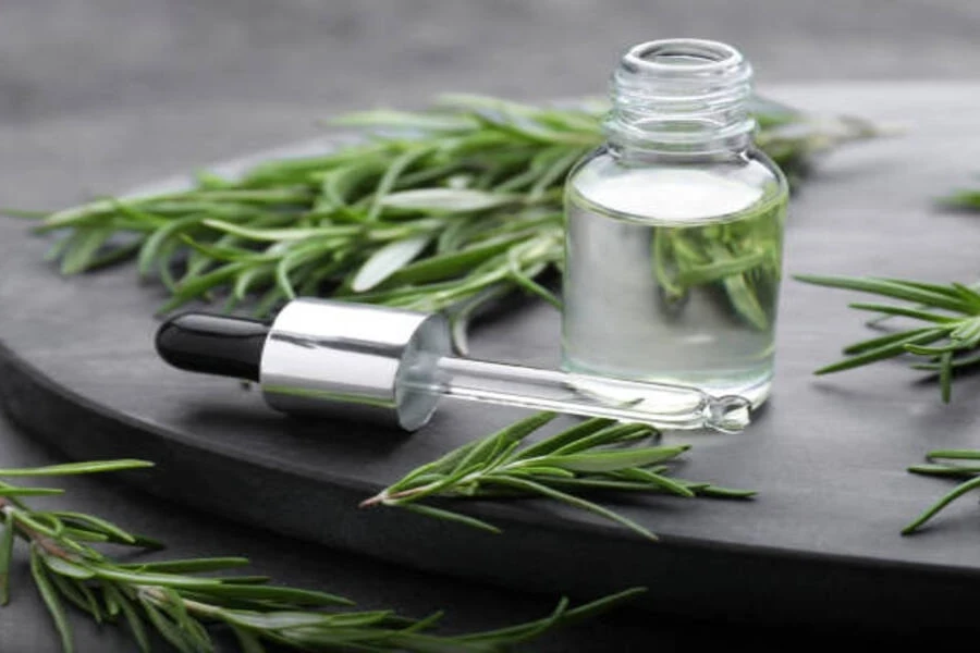 Rosemary water in vial surrounded by fresh leaves