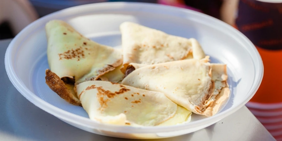 Tasty hotcakes with filling in round shaped plastic plate on a table in sunlight on a blurred background