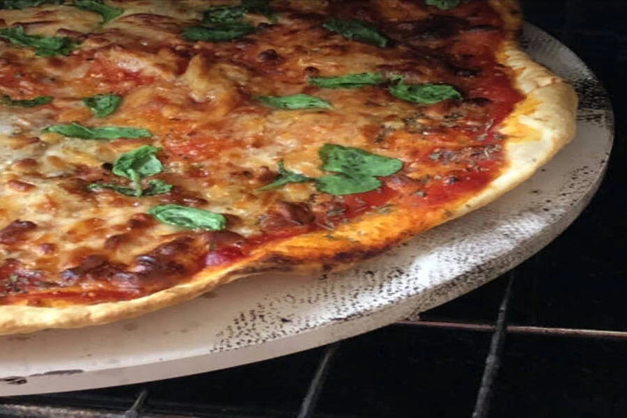 Thin pizza with mozzarella cheese and tomato on white stone
