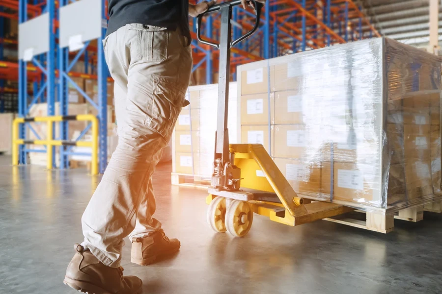 Warehouse worker using a manual pallet truck