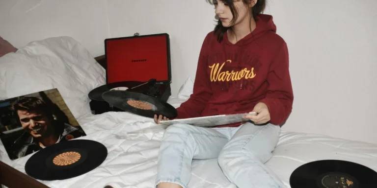 Woman Sitting on Bed Holding Vinyl Records