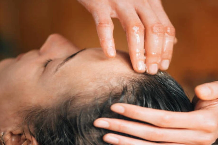 Woman getting scalp massage treatment using rosemary oil