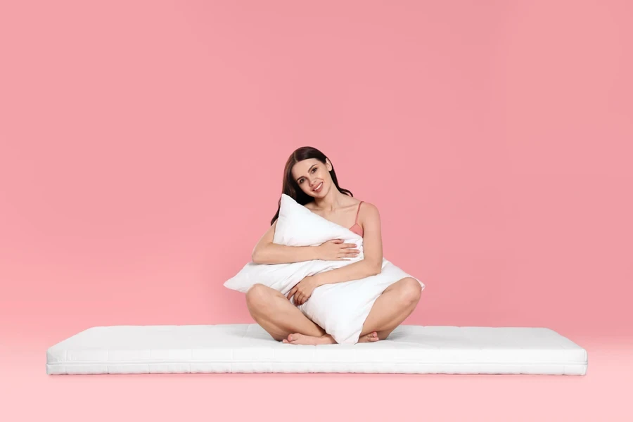Young woman on a mattress hugging a pillow