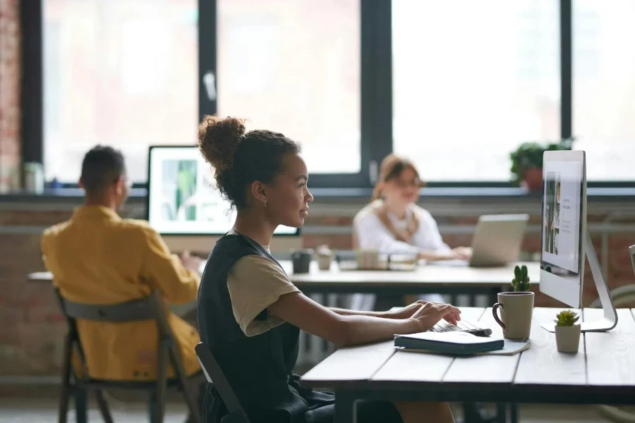 A girl working on a computer with two people in the background
