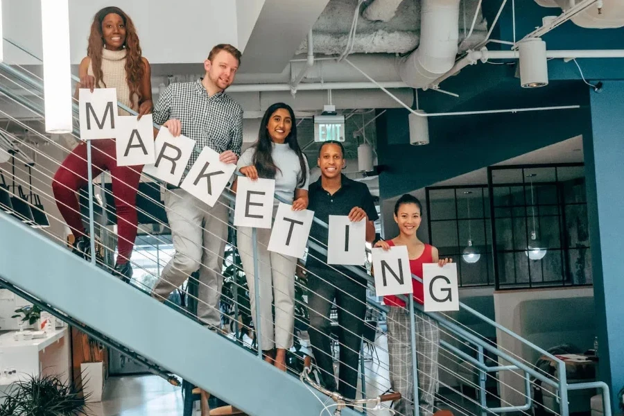 A group holding "MARKETING" signs while standing on stairs