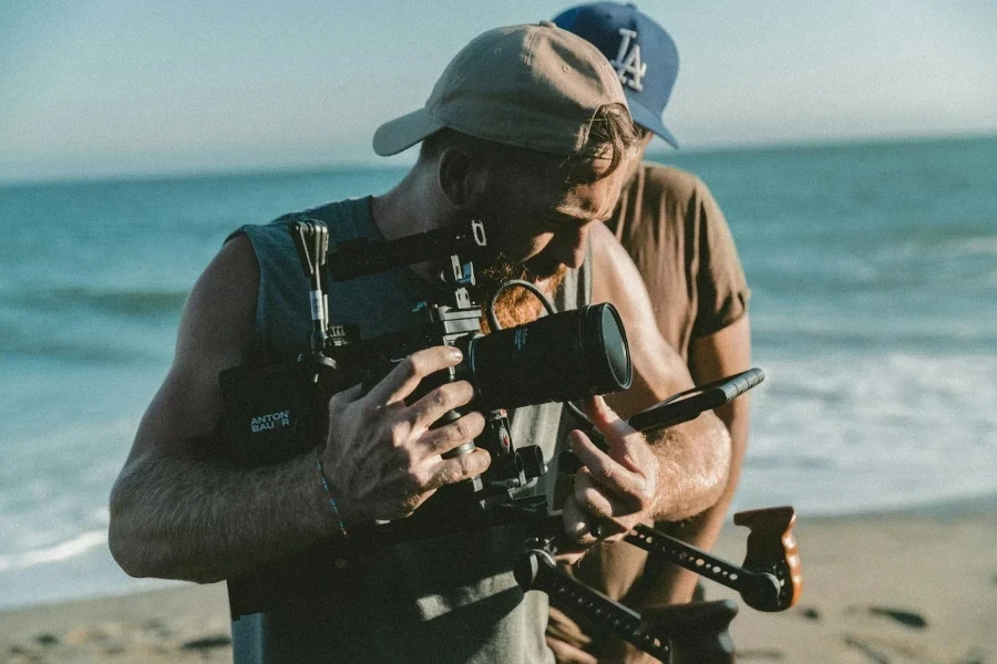 A man holding a video camera near the sea