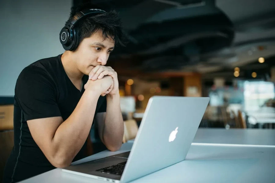 A man wearing headphones and sitting in front of a macbook