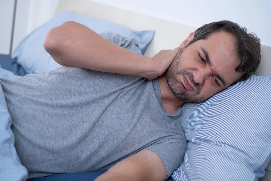 man on a bed with neck ache