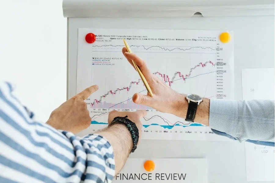 People’s hands pointing at a chart on a whiteboard