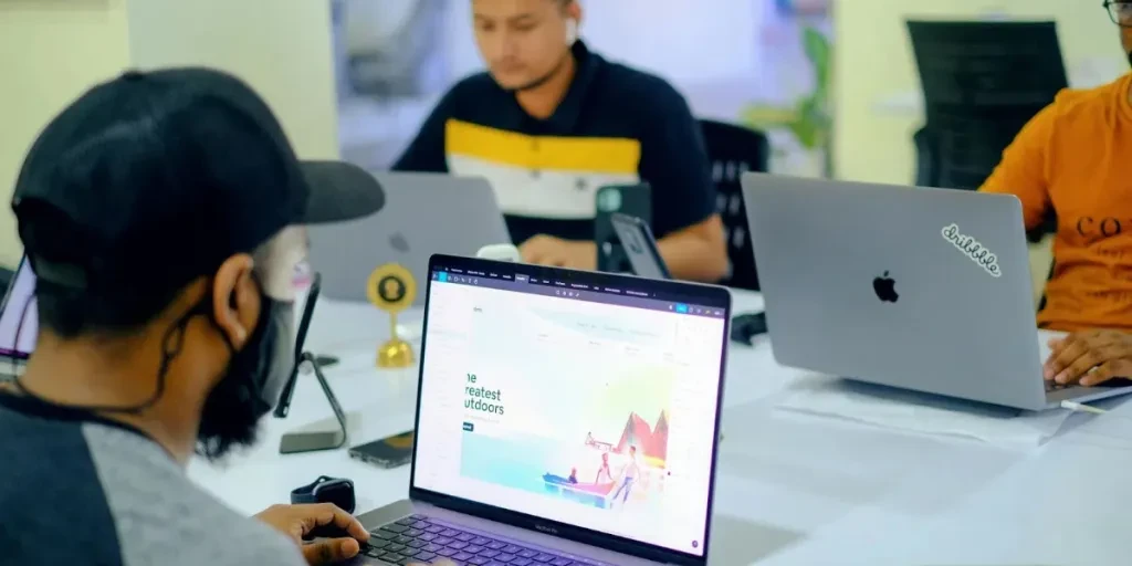 Three people working on a laptop