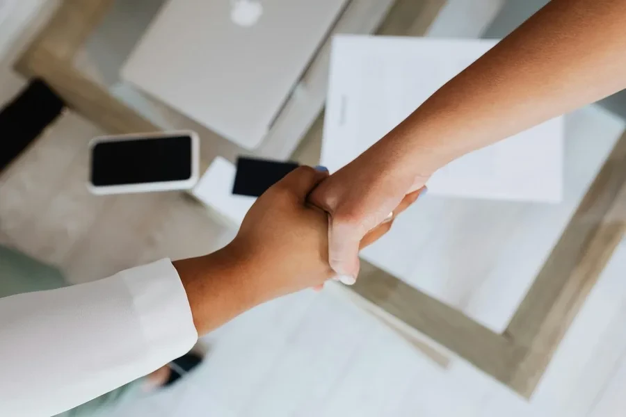 Two people shaking hands over documents