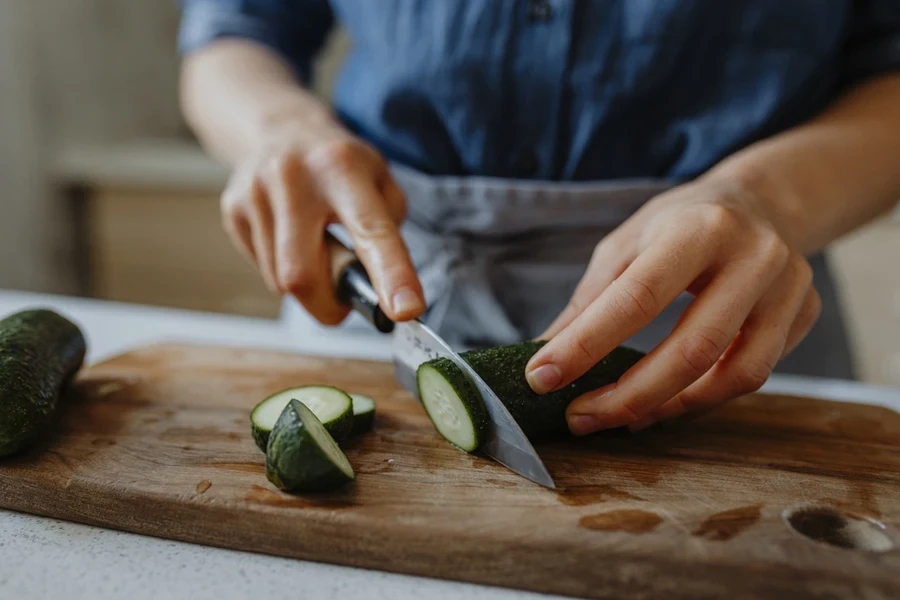 woman slicing a cucumber with a knife