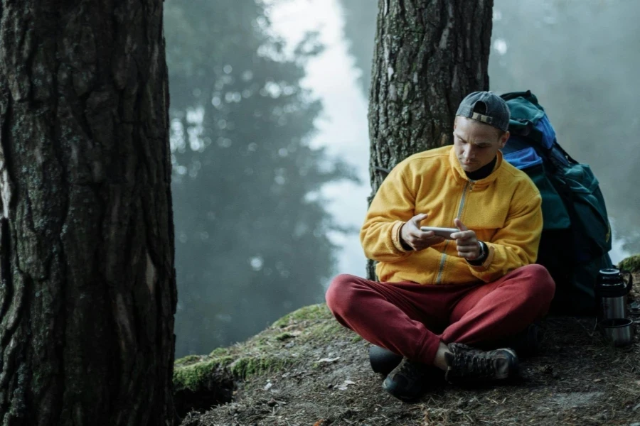 A Man using a Smartphone while Sitting on the Ground Near a River