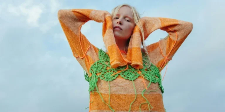 Una mujer con un suéter de punto naranja y una blusa de crochet verde